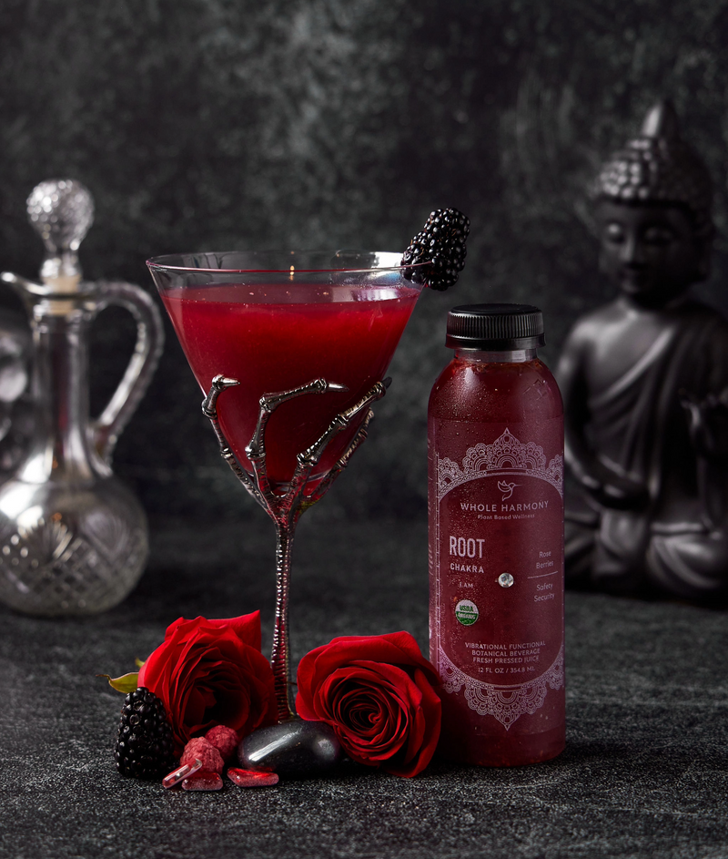 Root Chakra balancing beverage next to a mixed drink, roses, berries and stones. A buddha in the background.